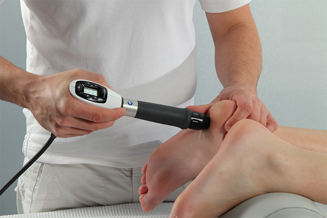 A professional using a handheld device to scan a person s foot during a medical examination.