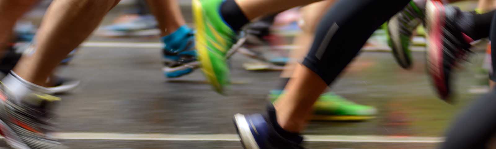 The image shows a group of runners participating in a race on a wet road.