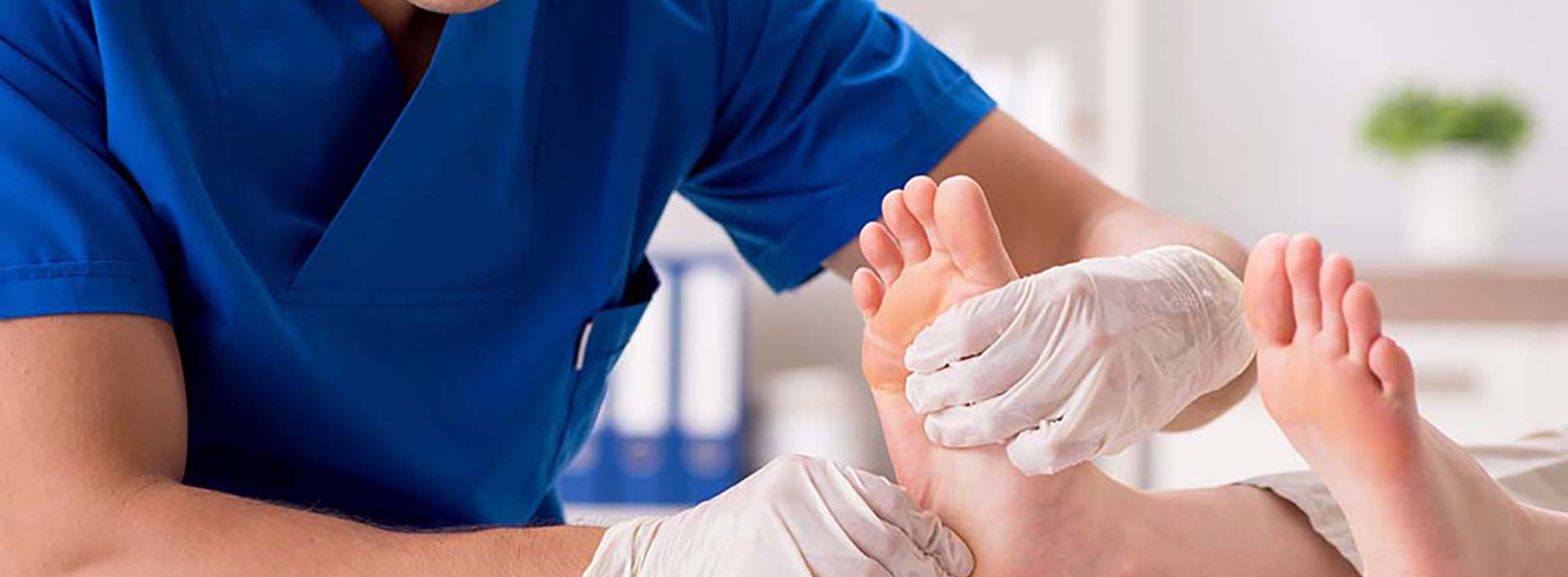 A male podiatrist performing foot care on a patient s feet in a clinical setting.