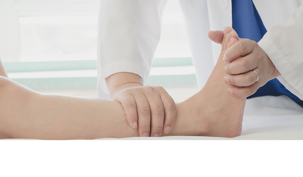 An adult receiving foot massage from another person, both seated with hands on feet.