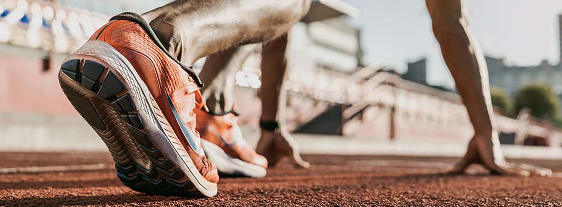 A person jogging on a track with their feet off the ground, wearing running shoes.