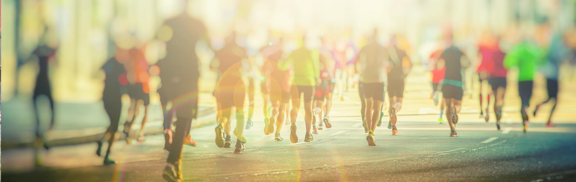 The image shows a group of runners participating in an outdoor race or event, captured from a distance with a shallow depth of field, emphasizing the motion of the runners against a blurred background.